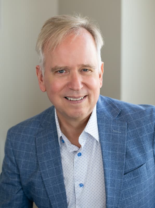 Dr. Marty Ross, MD, smiling in a blue suit and white patterned shirt